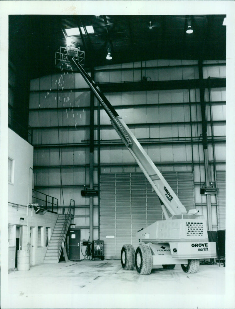 A Grove manlift is being moved forward on a mining site. - Vintage Photograph