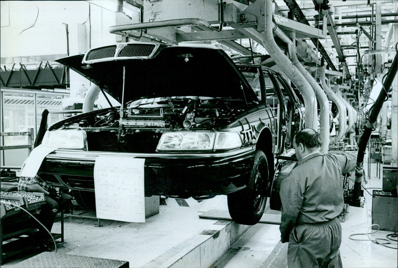 Workers assemble cars on the assembly line at the Rover plant in Oxford, England. - Vintage Photograph