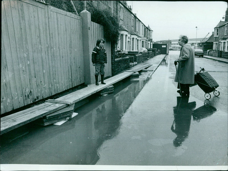 A man and woman conversing across floodwaters in Osney. - Vintage Photograph