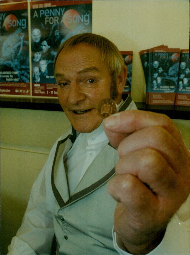 Actor Julian Glover holds a penny outside the Oxford Playhouse theatre. - Vintage Photograph