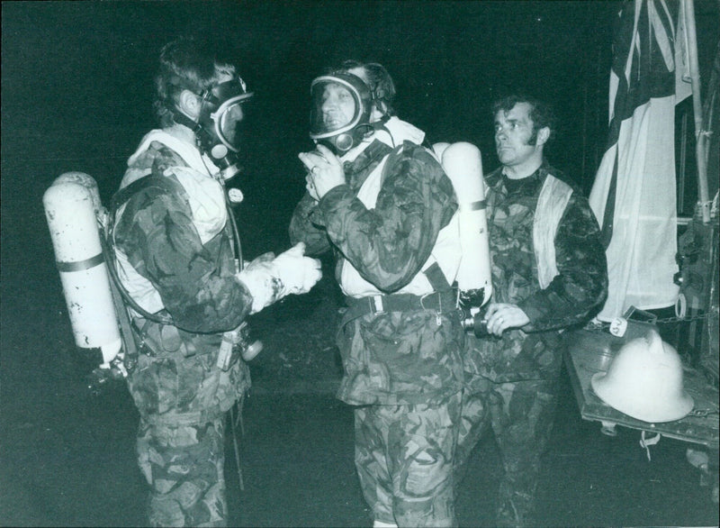 Firefighters don breathing gear before entering a smoke-filled building in Oxford Mail. - Vintage Photograph