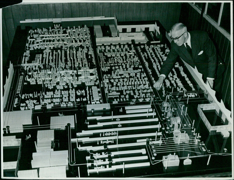 Mr. J. Troman, a planning draughtsman, moves a model machine in a model of 'K' Block Extension. - Vintage Photograph