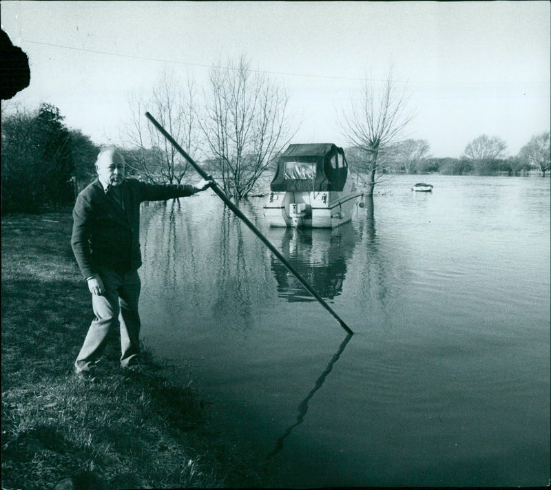 Mr. Jack Bunn, licensee of The Maybush, checks the depth of water over his lawn in Newbridge. - Vintage Photograph