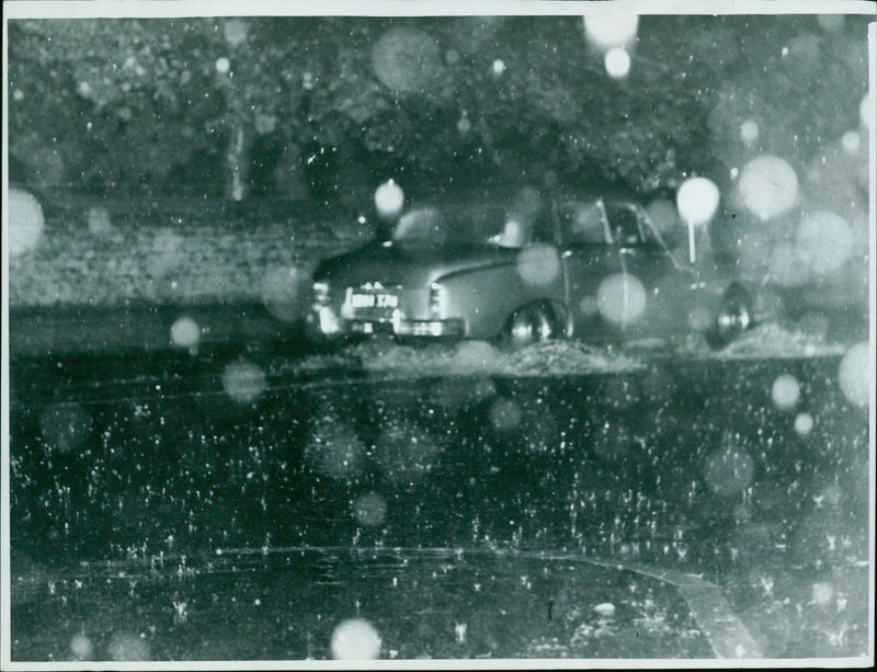 A car drives on a flooded London Road in Headington during a severe storm. - Vintage Photograph