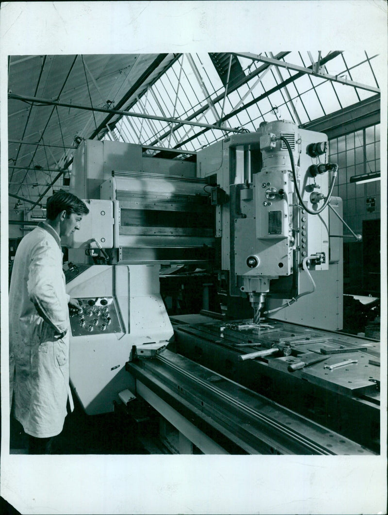 A worker operating numerical controlled tooling in a factory. - Vintage Photograph