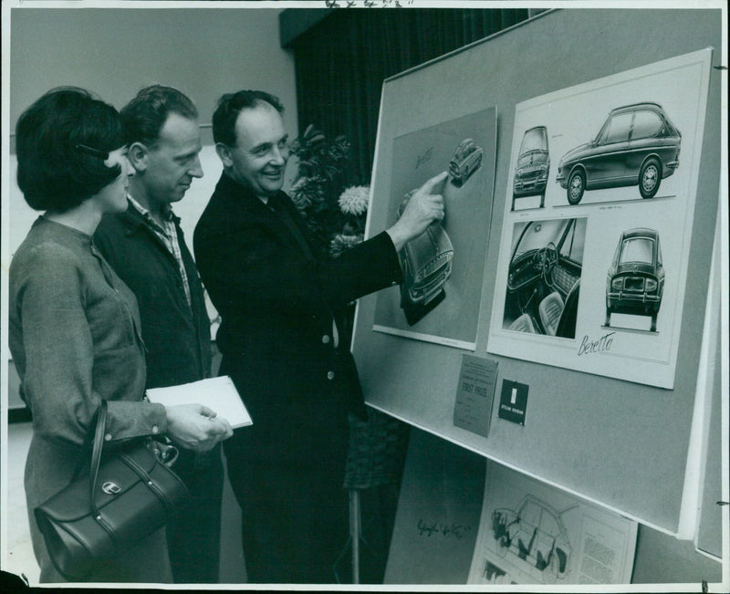 On display at the Pressed Steel Company in Cowley, three colleagues admire a prize-winning car design by Mr. C. R. Owen. - Vintage Photograph