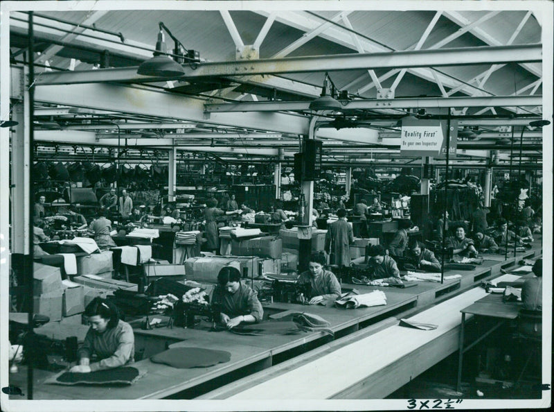 A worker inspects a product on the assembly line. - Vintage Photograph