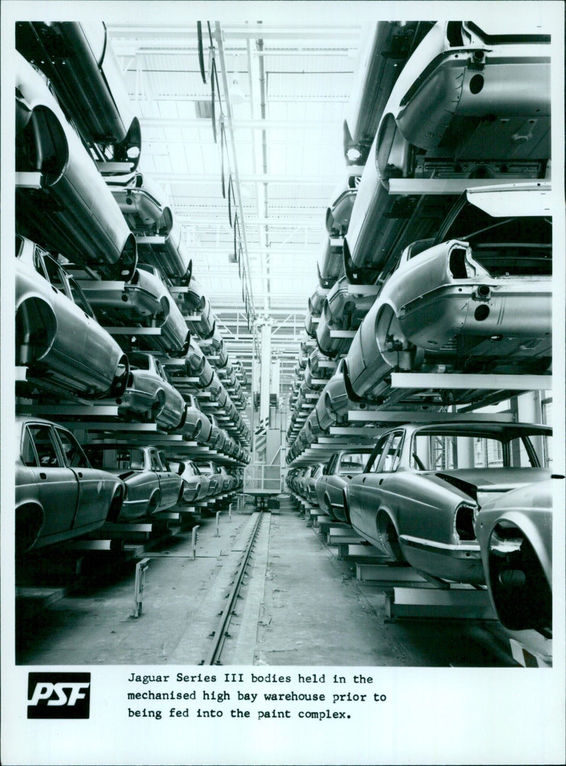 Workers prepare Jaguar Series III car bodies for painting in a mechanized warehouse. - Vintage Photograph