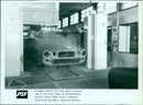 A Jaguar Series III body shell receives a coat of thermoplastic acrylic paint. - Vintage Photograph