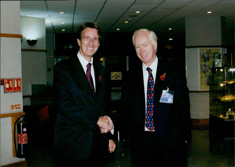 Parliamentary Undersecretary of State for the Department of Education and Employment Michael Wills being greeted by Unipart Group Chief Executive John Neill. - Vintage Photograph