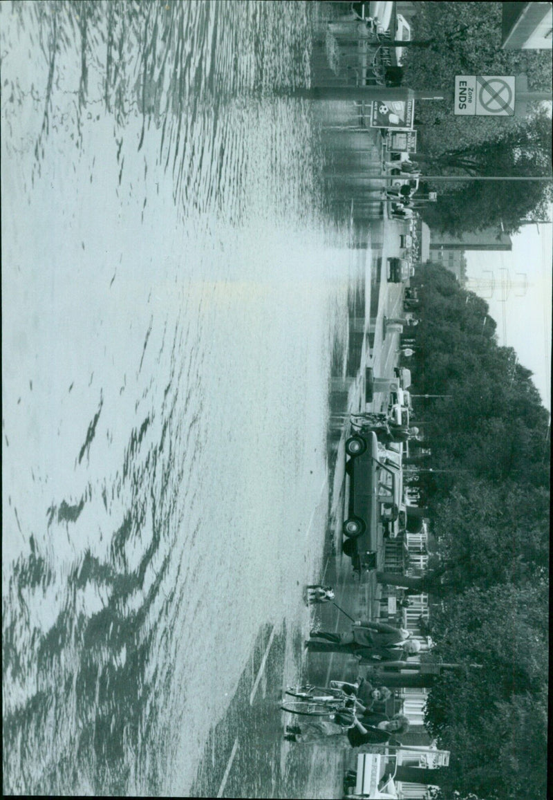 Residents of a flooded neighborhood in Delhi, India, are seen navigating the waters on foot and by bicycle. - Vintage Photograph