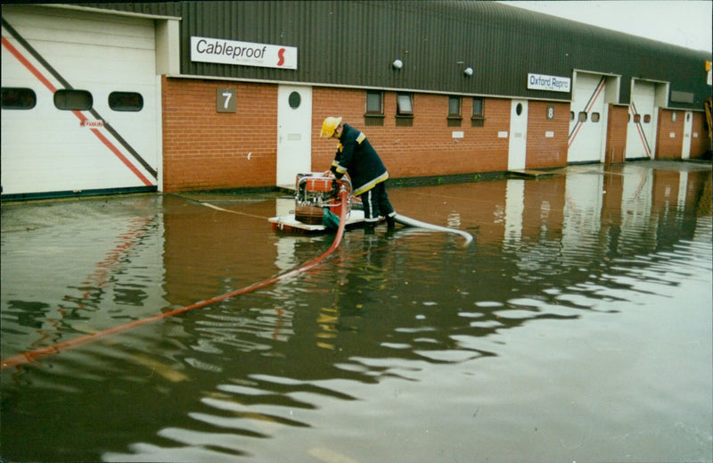 Rescue workers using pumping equipment to help children during floods in Oxford, England. - Vintage Photograph