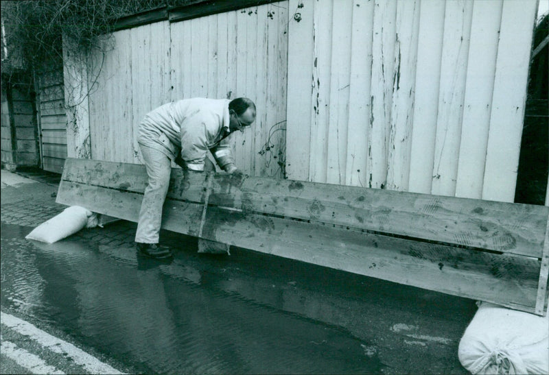 Phillip Clatworthy, charge hand with Engineering Services with the council, lays out sandbags and boards on Bridge Street in Osney Island. - Vintage Photograph