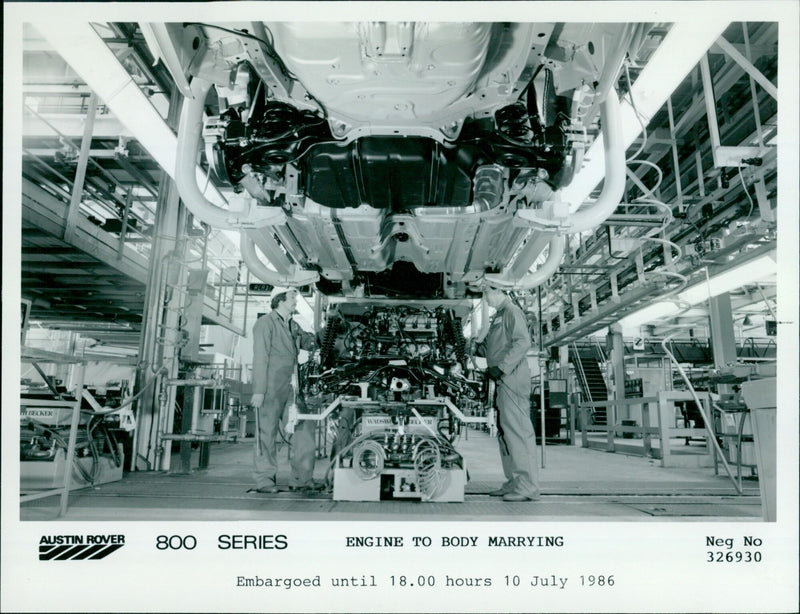 Workers marry the engine and body of a Becker Austin Rover Ready 800 Series car. - Vintage Photograph