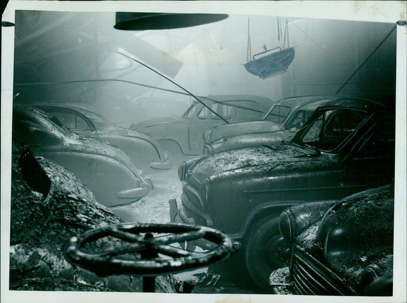 A picture of the fire-swept transit shed at Nuffield Exports, Ltd. in Cowley, showing damaged vehicles. - Vintage Photograph