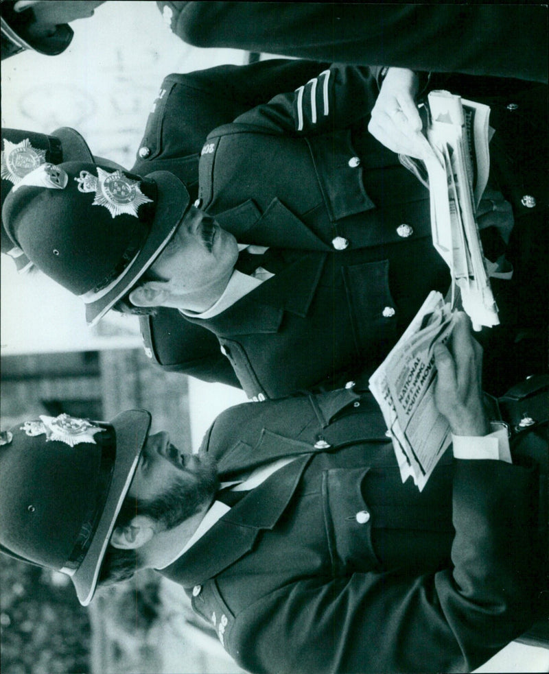 Police officers examine leaflets confiscated from Black Movement members during an arrest. - Vintage Photograph