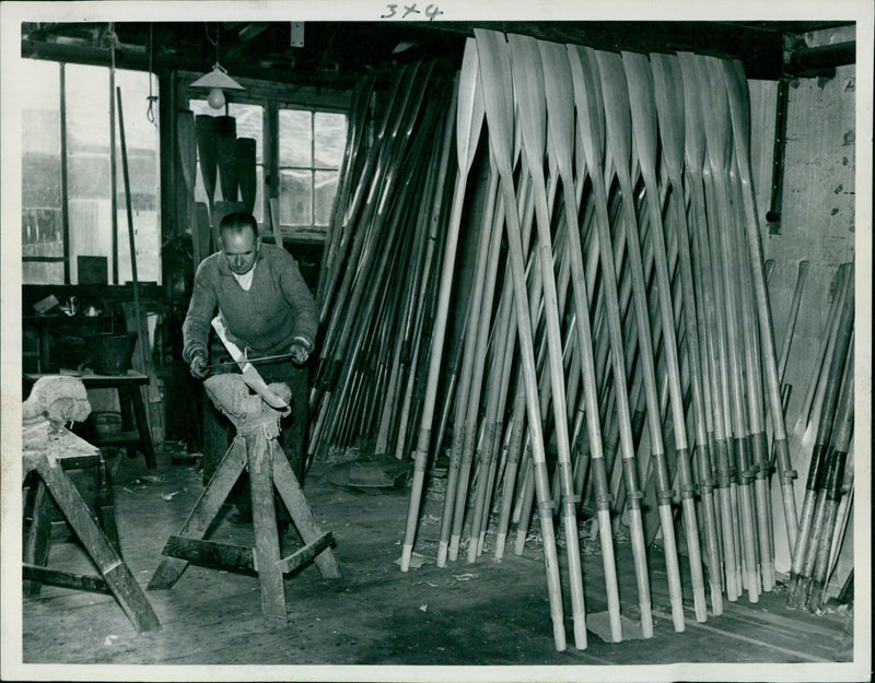 A craftsman shapes an oar with a trained eye for perfection. - Vintage Photograph