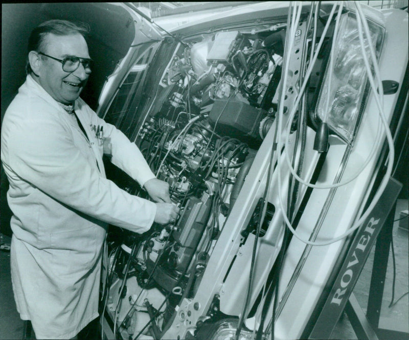 Neville Buckett linking up cables to a diagnostic computer for an upturned Rover 800 engine. - Vintage Photograph