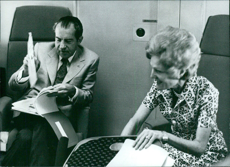 President and Mrs. Richard Nixon on board aircraft reminiscing over press cuttings - Vintage Photograph