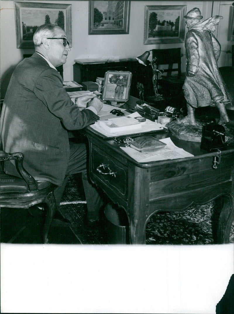 Maurice Chevalier in his office with a photo of his mother and a statue of Clemenceau - Vintage Photograph