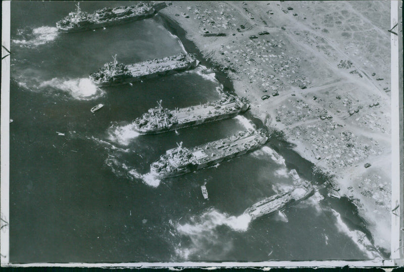 A photo of US landing ships unloading supplies on the beach of Iwo Jima where US Marines landed, 1945. - Vintage Photograph