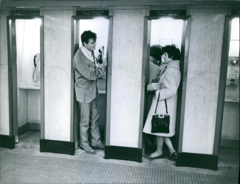 German actor, Horst Buchholz talking to a lady in a telephone booth. - Vintage Photograph