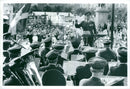 Military music concert, military men standing and playing band and people gathered. - Vintage Photograph