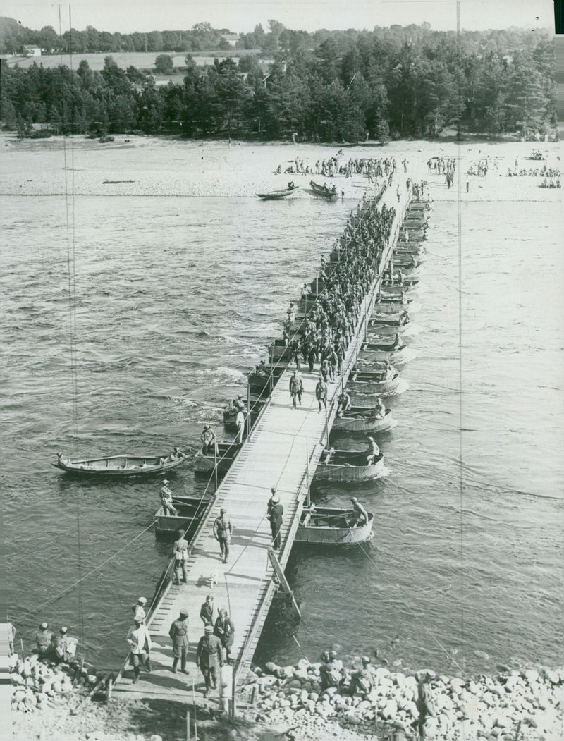 Soldiers marching across a war bridge built by the Svealand Engineer Regiment. - Vintage Photograph