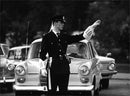 Policeman directs traffic with signs that many do not understand, shows a study of the transition from left to right traffic - Vintage Photograph