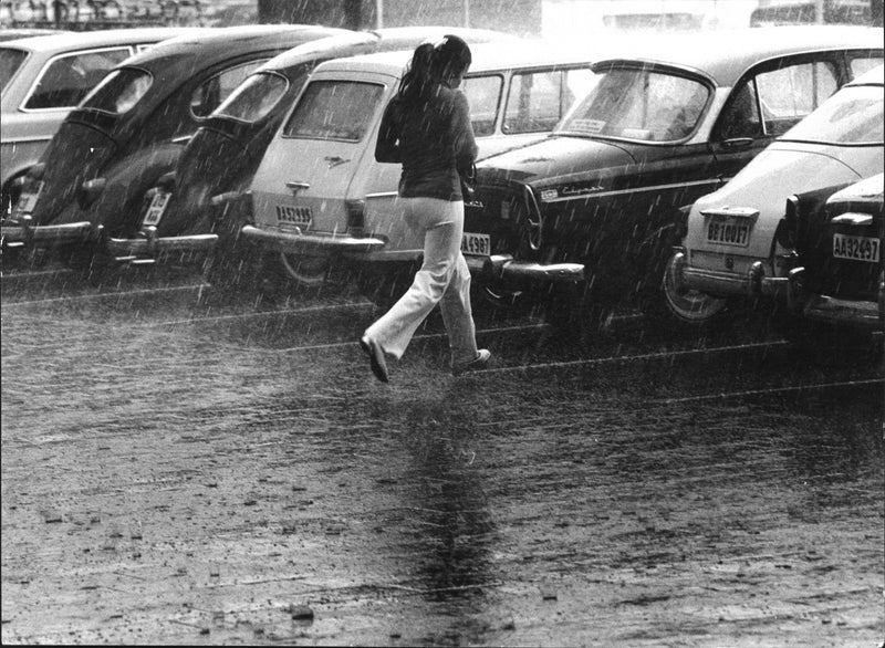 Girl running toward the cars in the pouring rain - Vintage Photograph