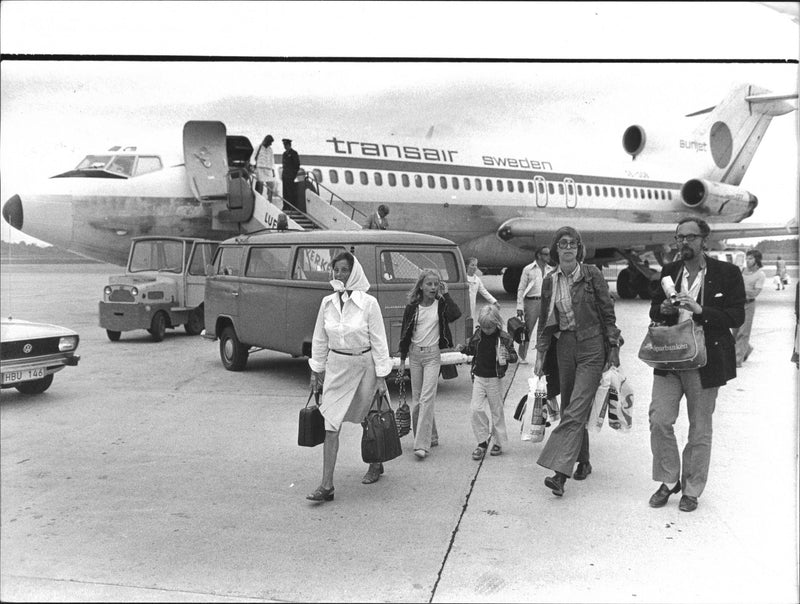 Passengers alighting at the charter plane from Transair. - Vintage Photograph