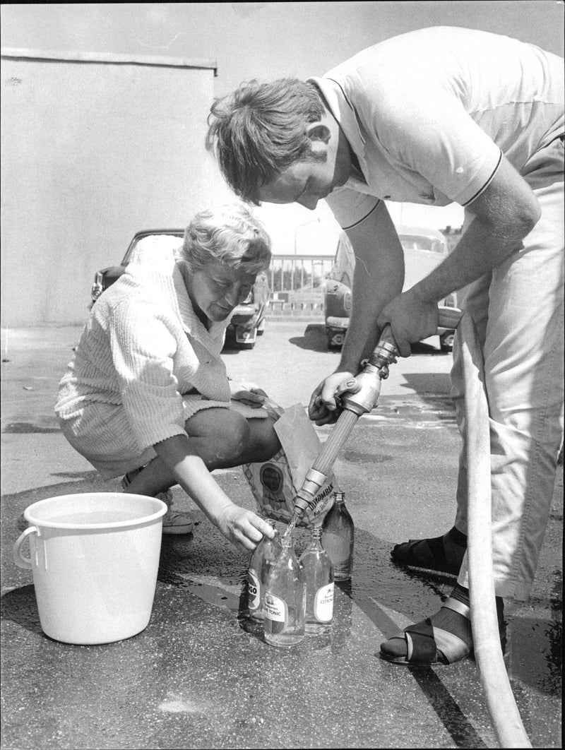 Stockholmare utan vatten efter att en huvudlinje bröt. Här fru Marianne Box Kaffevatten från en tankbil i Rågsved. - Vintage Photograph