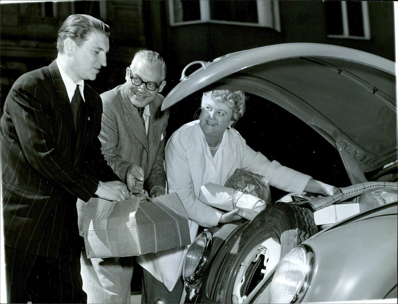 Happy men and women, loading into the cargo compartment of a Volkswagen. - Vintage Photograph