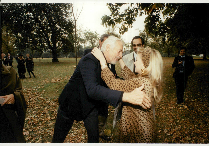 Actor James Coburn embraces her old flame singer Lynsey de Paul during a tree-planting ceremony in Hyde Park - Vintage Photograph