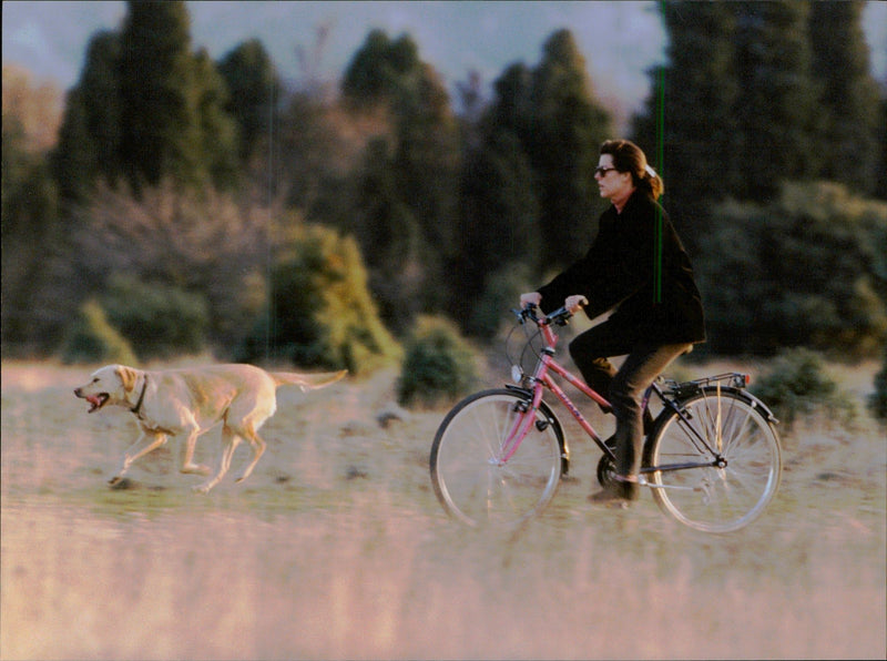 Princess Caroline of Monaco bicycles in the countryside with her two dogs. - Vintage Photograph
