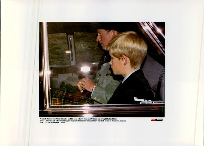 Prince Charles in the back seat of a car with Harry&