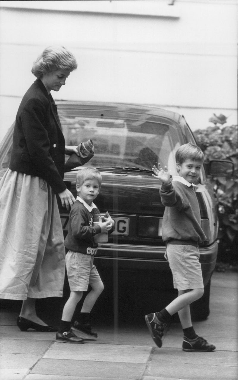 On the way to school. Prince William waves the camera while Prince Harry goes close to his mother, Princess Diana. - Vintage Photograph