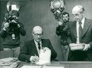 Literature Prize winner Odysseus Elytis assisted by lawyer Bengt Bjerke th signs his books while TV documents the event in audio and video - Vintage Photograph