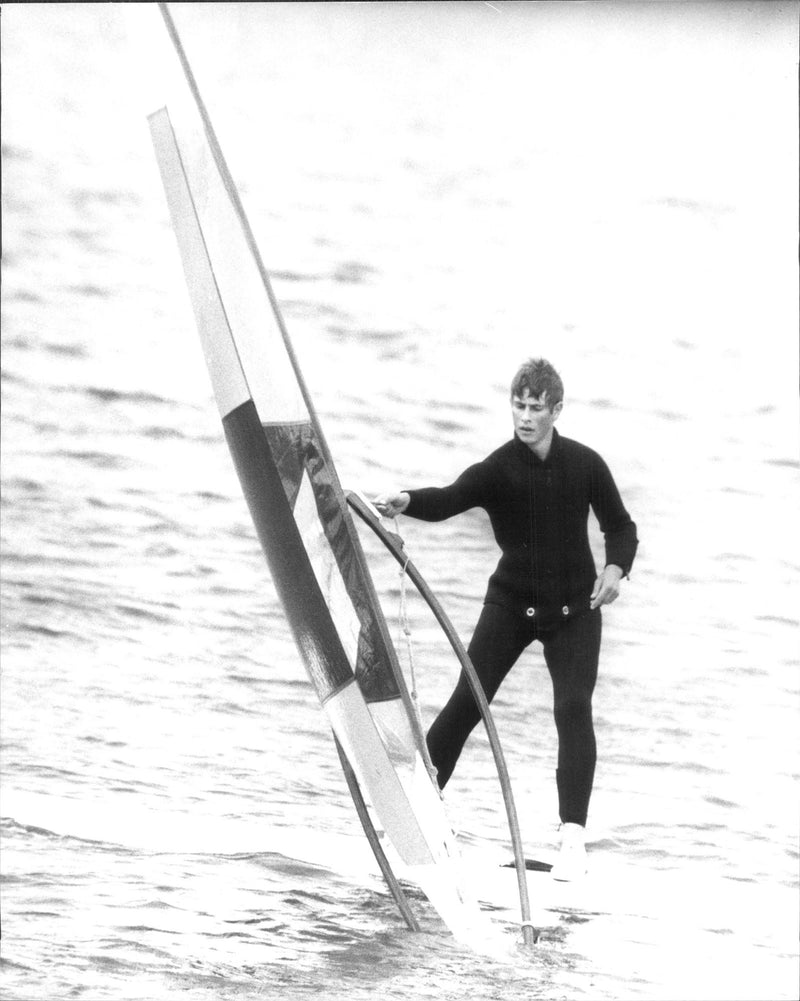 Prince Edward tries on windsurfing outside Cowes. Prince Charles acted as teacher of his younger brother and ex-King Constantine of Greece. - Vintage Photograph