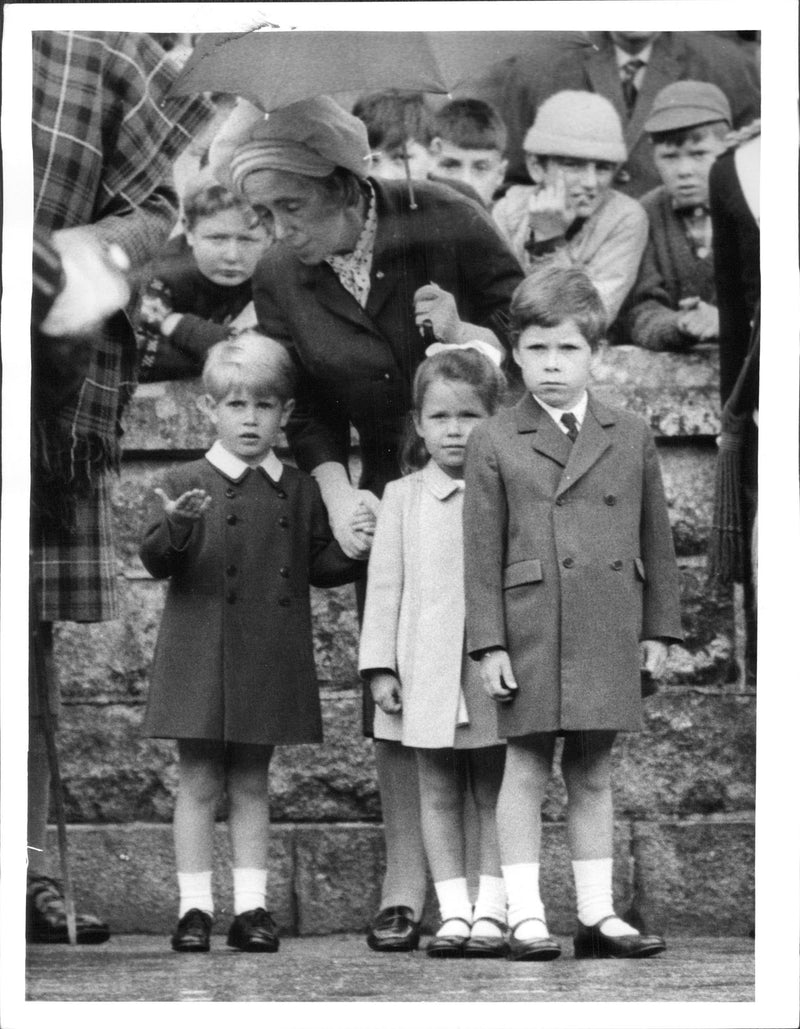 Prince Edward in the far right, investigates whether it has stopped raining while watching his mother Queen Elizabeth inspect the guardian. - Vintage Photograph