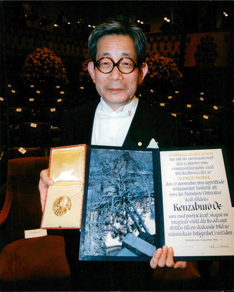 Portrait image of Japanese writer Kenzaburo Oe, winner of the Nobel Prize in Literature in 1994, shows his prizes. - Vintage Photograph