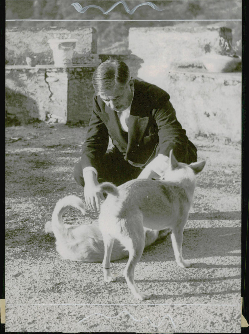 French politician Pierre Laval along with one of his dogs outside the castle he has as a residence. - 10 September 1944 - Vintage Photograph