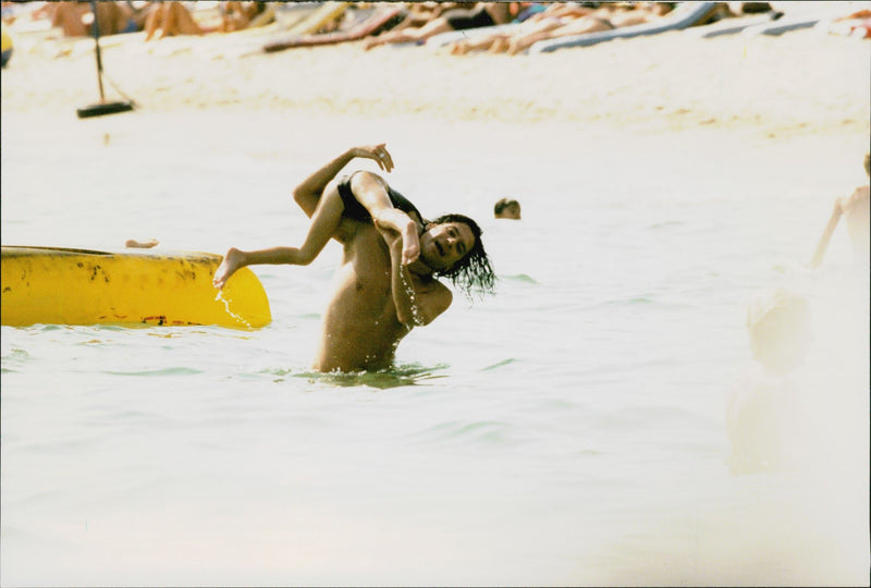 Singer Michael Hutchence is bathing together with daughter Tiger Lily. - Vintage Photograph