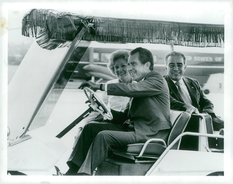 RIchard Nixon runs a golf car and next to him sits his wife, Pat Nixon. - Vintage Photograph