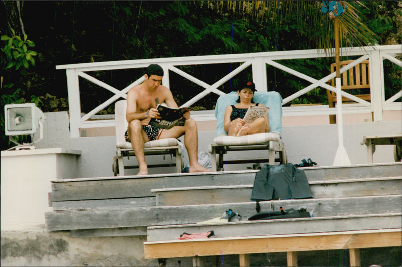 Eric Cantona och frun Isabelle lÃ¤ser varsin tidning under deras semester. - Vintage Photograph