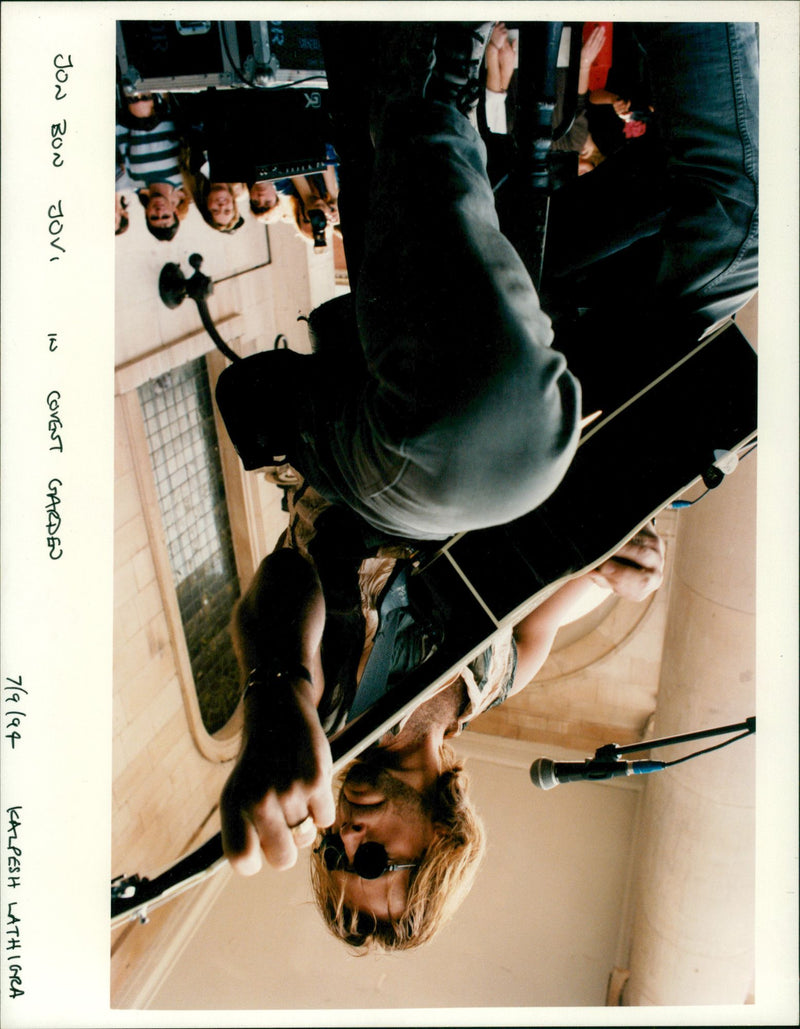 Bon Jovi playing guitar while singing at garden busk. - Vintage Photograph