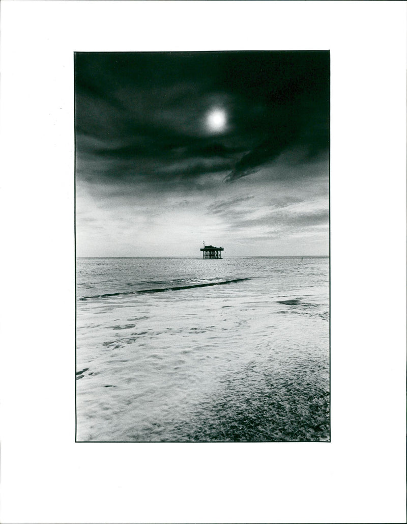 Dark clouds around the sun over the coastline - Vintage Photograph